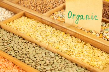 The collection of different groats, peas, buckwheat, wheat and lentils in the wooden box with notice organic.