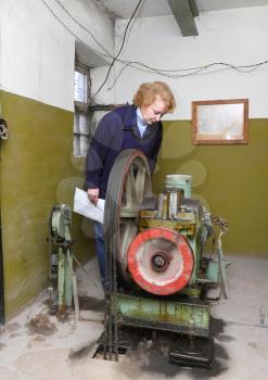 Operator woman-engineer in machine room (elevator) check the mechanical equipment.