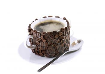 The cup of coffee and spoon,decorated by grains of coffee. Isolated