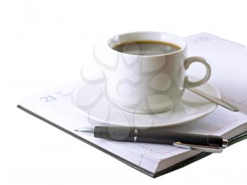 Coffee cup, standing on the opened daily organizer . Isolated