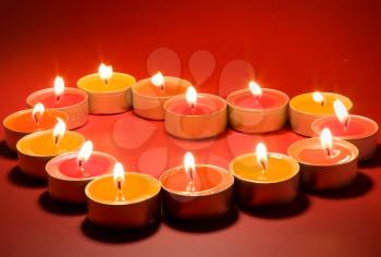 Small light candles, in heart form on a red background.