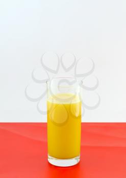 Glass of fresh orange juice with squeeze slice on redbackground.