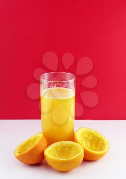 Glass of fresh orange juice with squeeze slice on red background..