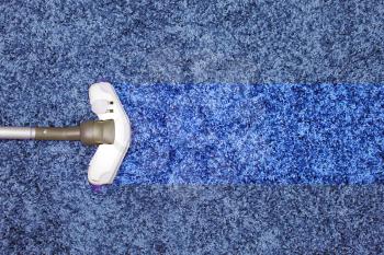 The metal pipe of vacuum cleaner in action - clean stripe on the carpet.