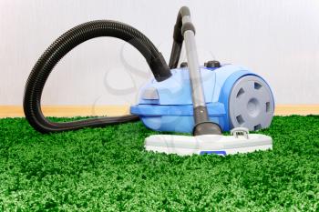 Vacuum cleaner stand  on green  carpet