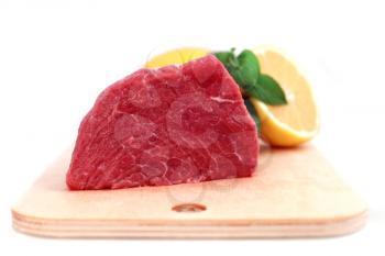 Beef steak  on meat hardboard with green leaf and lemon. Isolated.