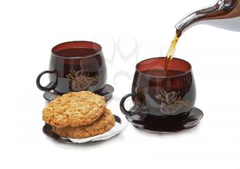 Still life - cookies, two cups and pouring tea. Isolated.