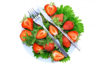 A fresh strawberries with fork and knife on green foliage . Isolated