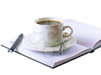 Coffee cup, standing on the opened daily organizer . Isolated