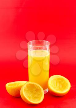 Glass of fresh orange juice with squeeze slice on red background..