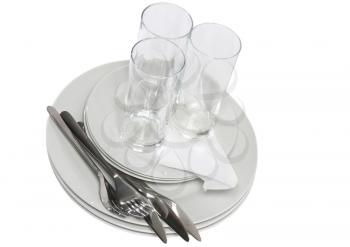 Pile of white plates, glasses with forks and spoons on silk napkin. Isolated over white