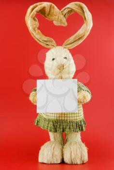 Straw hare with ears in the form of heart on a red background with the white nameplate.