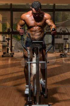 male bodybuilder using the elliptical machine
