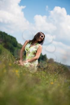 young woman in dress sitting on the grass
