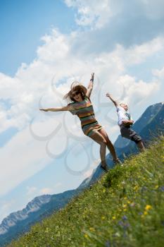 mother and son jumping in meadow