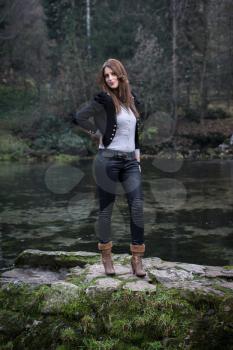 young woman in jacket standing and posing at the lake