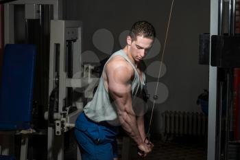 young bodybuilder doing heavy weight exercise for triceps with cable