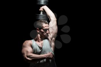 young bodybuilder doing heavy weight exercise for Shoulder on black background