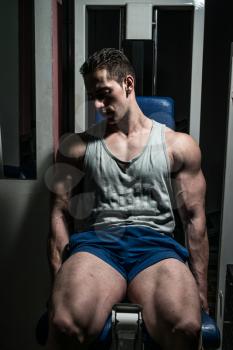 bodybuilder doing heavy weight exercise for legs on machine leg extensions