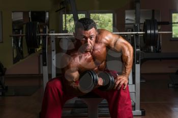 shirtless bodybuilder doing heavy weight exercise for biceps