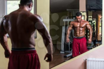 shirtless bodybuilder posing at the mirror