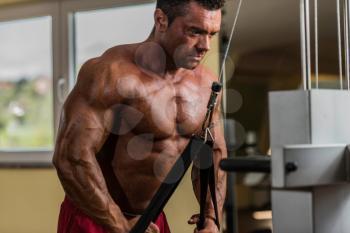 bodybuilder doing heavy weight exercise for triceps with cable