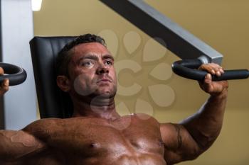 male bodybuilder doing heavy weight exercise for upper chest