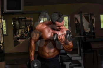 bodybuilder doing heavy weight exercise for biceps with dumbbell