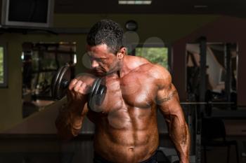 bodybuilder doing heavy weight exercise for biceps with dumbbell