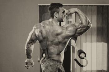 Bodybuilder Standing In The Gym And Flexing Muscles