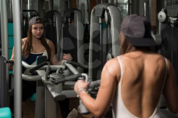 Young Woman Doing Heavy Weight Exercise For Back In Gym