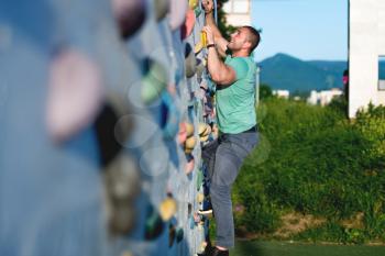 young man climbing wall rock outdoors