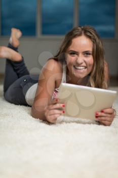 Happy Woman Using iPad While Lying On Carpet