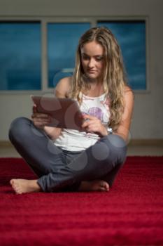 Happy Woman Using iPad While Siting On Carpet