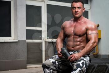 Bodybuilder Resting And Drinking Protein Shake after exercising in gym