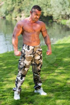 Bodybuilder Posing In A Field