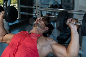 Man Doing Incline Chest Presses With Dumbbells In Gymnasium