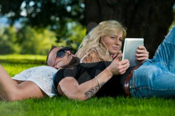 Young Couple Using A Digital Tablet In The Park
