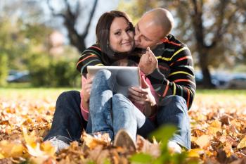 Happy Young Couple With Tablet Computer In The Park