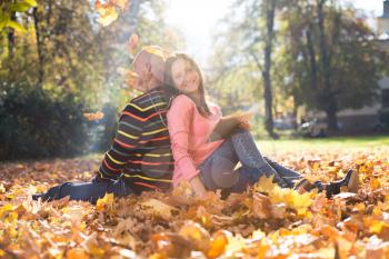 Couple Listening To Music And Throwing Leaves