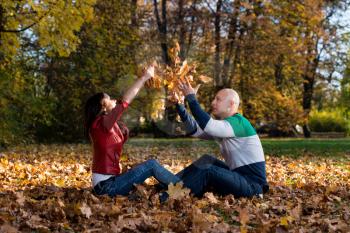 Couple Having Fun With Autumn Leaves In Garden