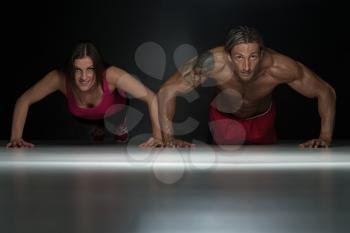 Couple Doing Pushups As Part Of Bodybuilding Training In A Studio