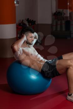 Attractive Men Doing Sit-Ups With Exercise Ball