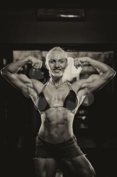 Serious Woman Bodybuilder Standing In The Gym And Flexing Muscles