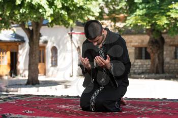 Young Muslim Man Making Traditional Prayer To God While Wearing A Traditional Cap Dishdasha