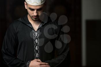 Young Muslim Guy Making Traditional Prayer To God While Wearing A Traditional Cap Dishdasha