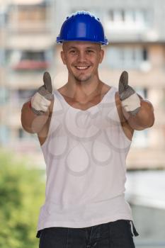 Portrait Of A Construction Worker With Blue Helmet Making Thumbs Up Sign