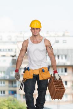 Worker With Protective Gear Wearing A Big Brick