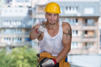 Portrait Of A Construction Worker With Yellow Helmet Making Thumbs Up Sign