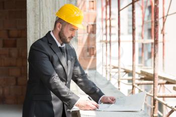 Portrait Of Construction Master With Yellow Helmet And Blueprint In Hands